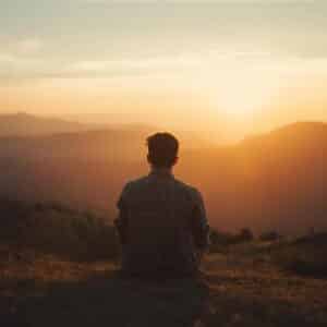 A person sitting alone on a hill during sunset, symbolizing peace, solitude, and self-reflection for Alone Captions for Instagram.